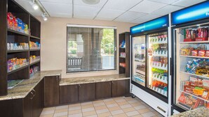 Una estación de autoservicio para bebidas con dispensadores refrigerados y estantes para aperitivos.