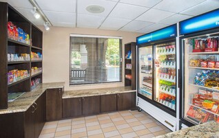 Una estación de autoservicio para bebidas con dispensadores refrigerados y estantes para aperitivos.