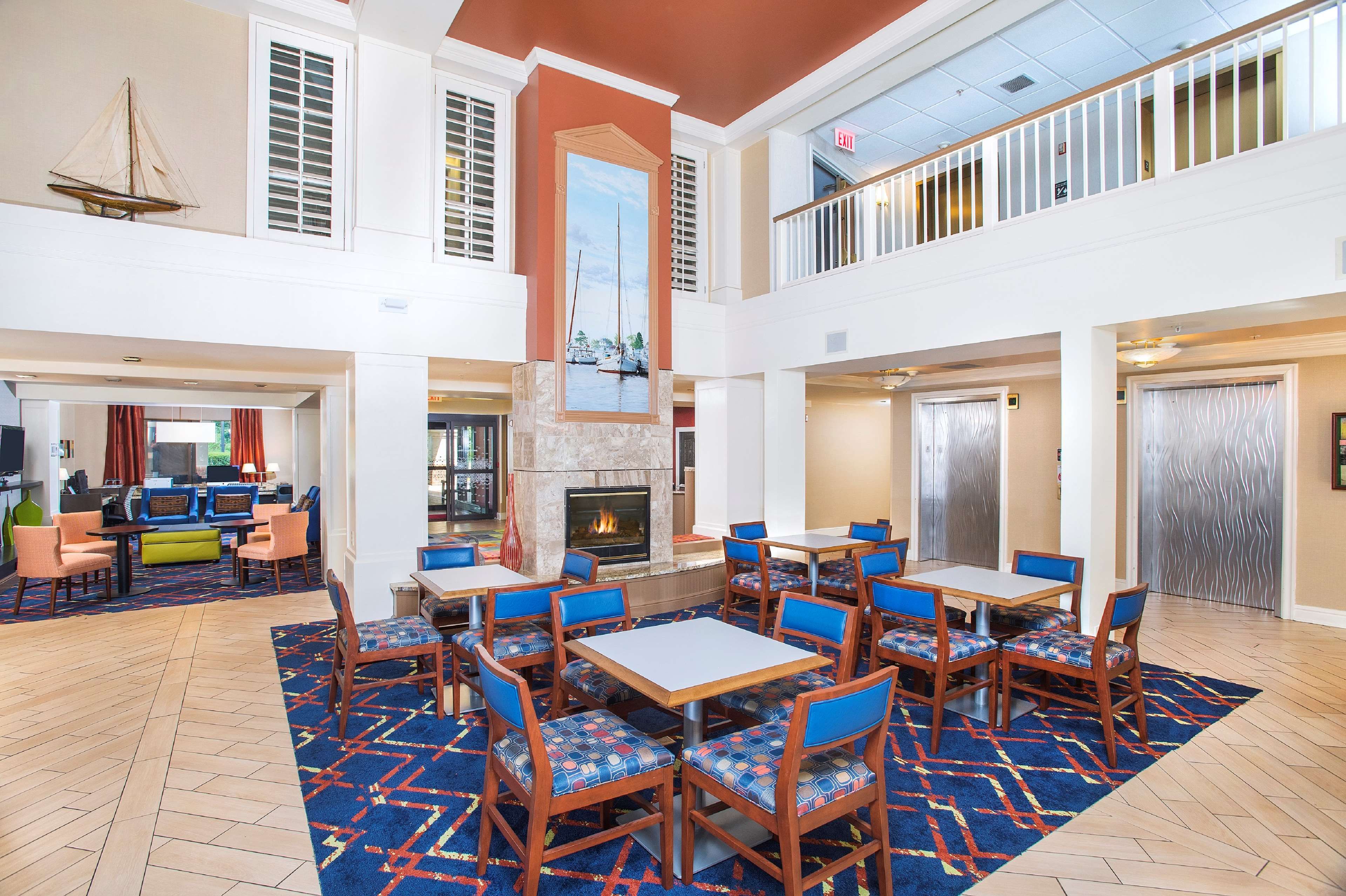 A spacious lobby with a fireplace, multiple seating areas, and a view of the upper floor.
