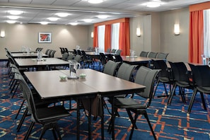 A conference room with multiple tables and chairs, arranged in rows, with a carpeted floor and a framed picture on the wall. - Hampton Inn & Suites Annapolis (Annapolis)