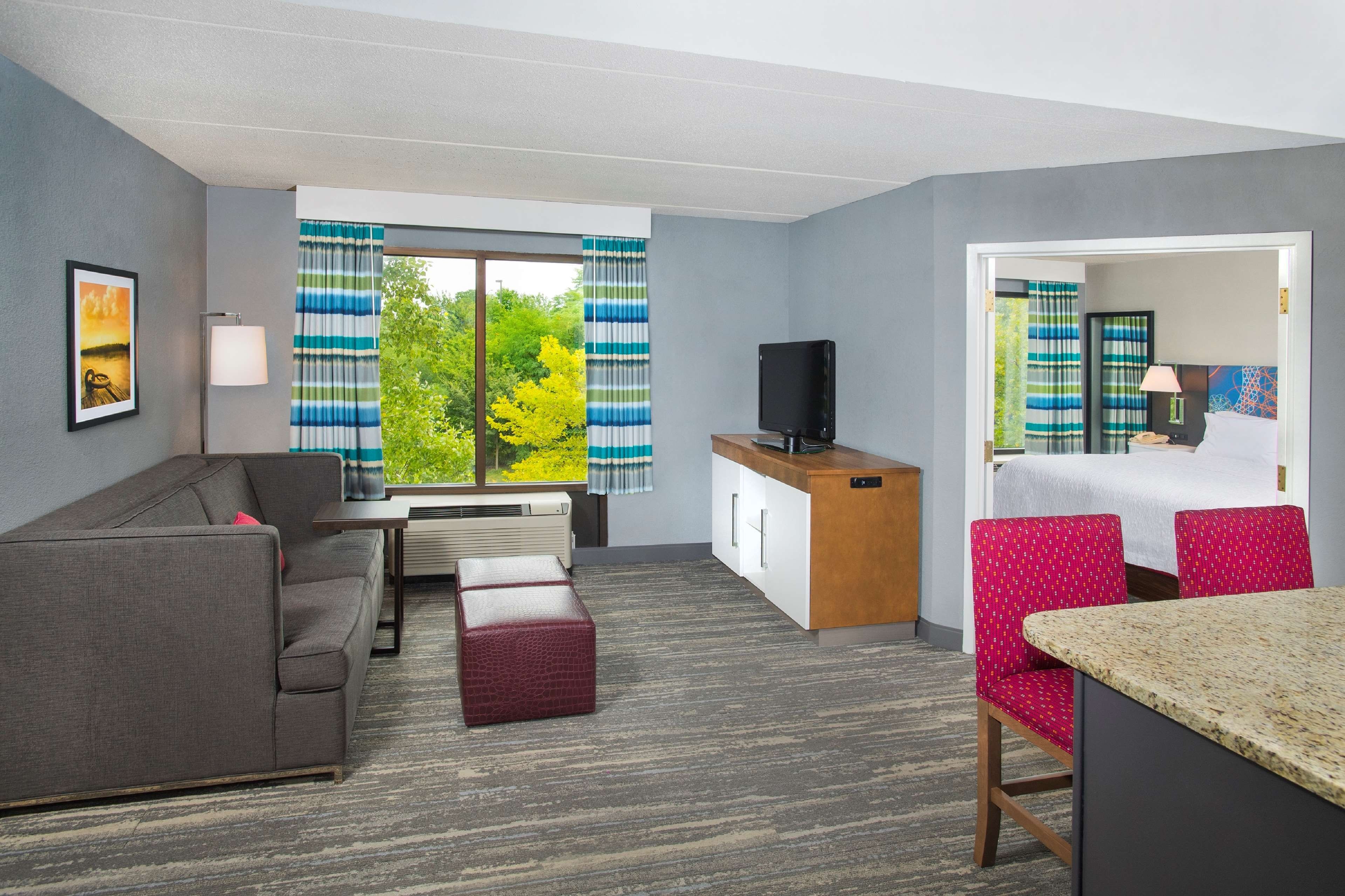 A hotel room with a sofa, a small table, a TV, a desk, a chair, and a bed.