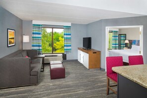 A hotel room with a sofa, a small table, a TV, a desk, a chair, and a bed. - Hampton Inn & Suites Annapolis (Annapolis)