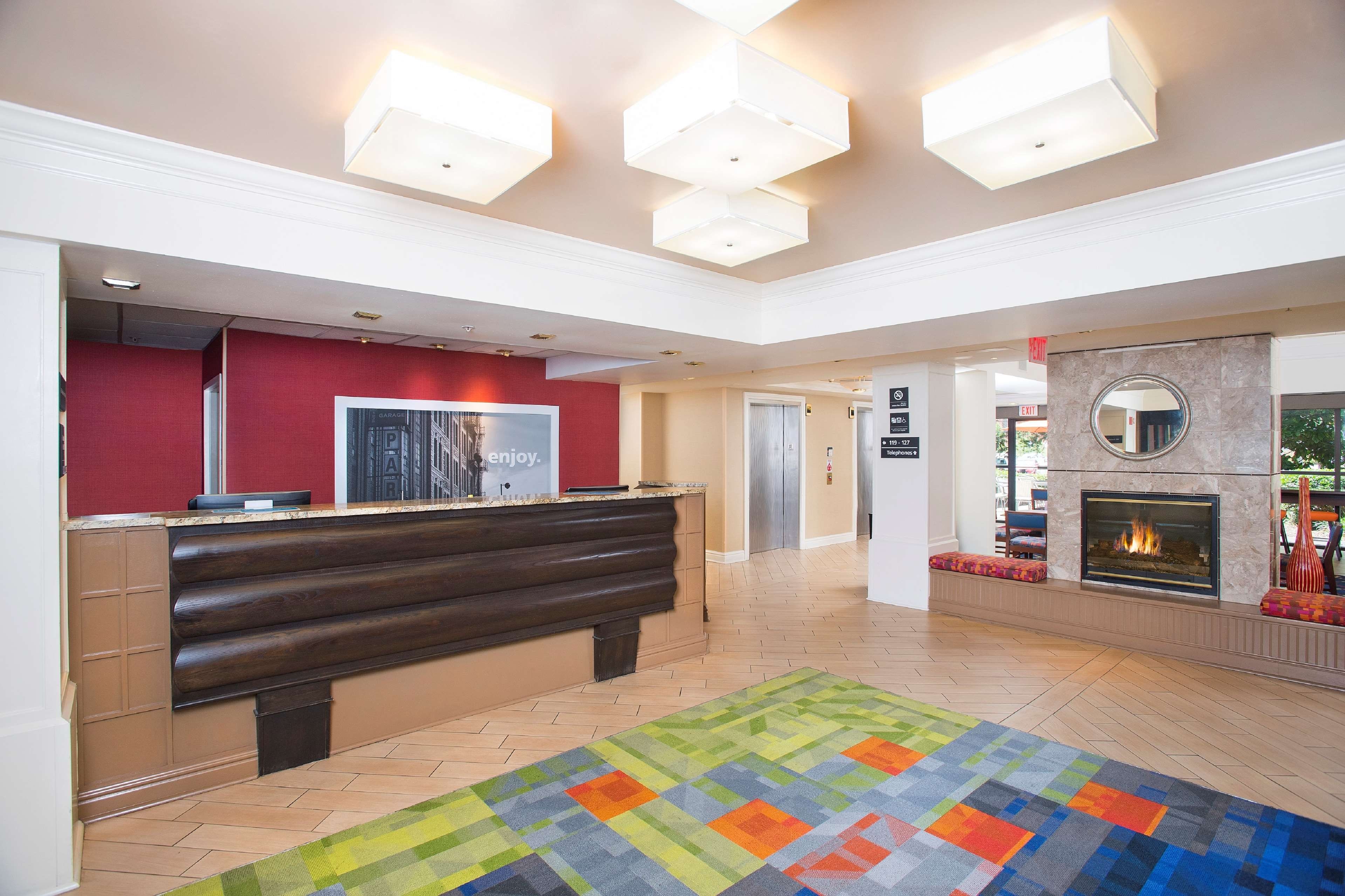 A hotel lobby with a reception desk, a fireplace, and a colorful rug.