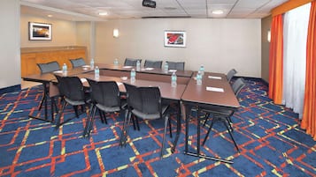 Une salle de conférence avec une longue table, des chaises, des bouteilles d’eau et un projecteur.