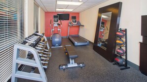 Un gimnasio con cintas de correr, elípticas, una banca y pesas sueltas.