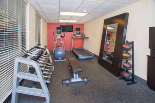 Un gimnasio con cintas de correr, elípticas, una banca y pesas sueltas.