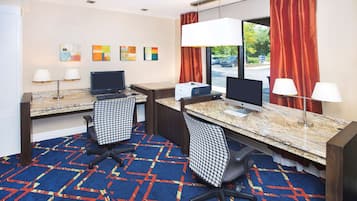 Une chambre d’hôtel avec deux bureaux, deux chaises, un sol recouvert de moquette et des œuvres d’art accrochées au mur.