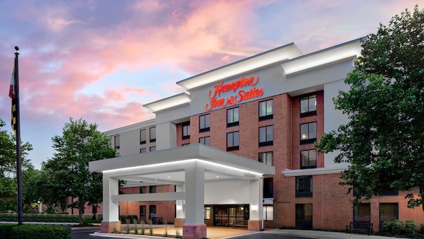 Un hotel Hampton Inn & Suites amb un disseny modern, que destaca per una entrada ben visible i una zona exterior coberta.