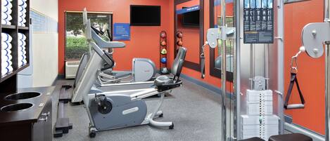 A gym with cardio machines, weightlifting equipment, and a bench.