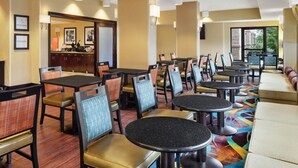 Eine Hotelhalle mit mehreren Sitzbereichen, darunter Tische und Stühle, sowie einer Rezeption.