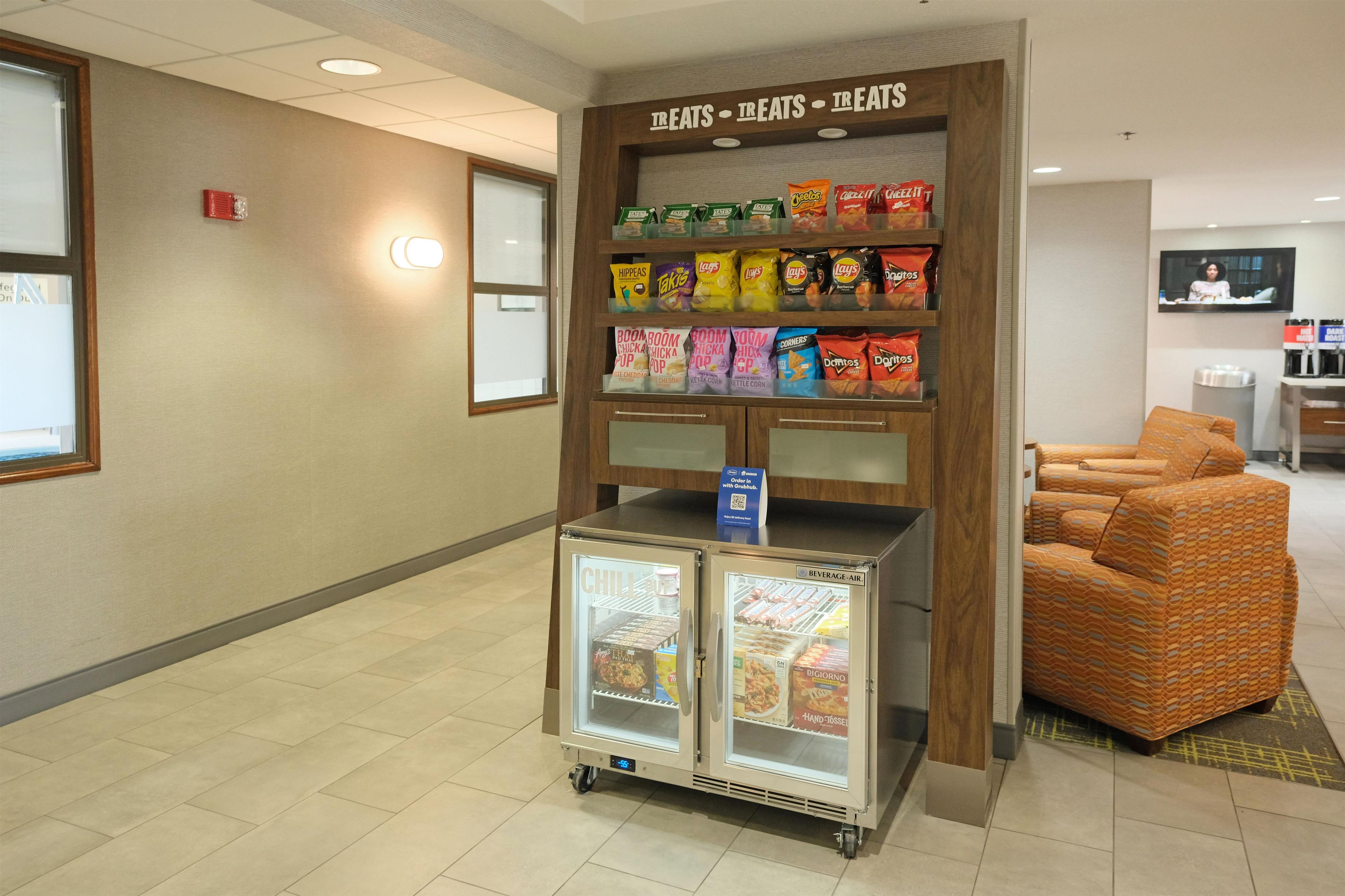 Eine Snacktheke mit verschiedenen Chips und einem Getränkekühler in der Hotelhalle.