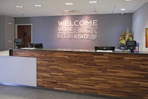 Un mostrador de recepción con un letrero que dice 'WELCOME TO THE BUCK EYE STATE', un mostrador de madera y un arreglo floral.