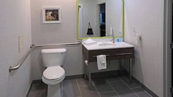 Un baño con inodoro, lavabo con espejo y perchero para toallas.