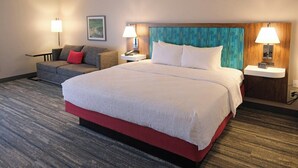 Habitación de hotel con una cama grande, dos mesitas de noche con lámparas, un sofá y un cuadro en la pared.