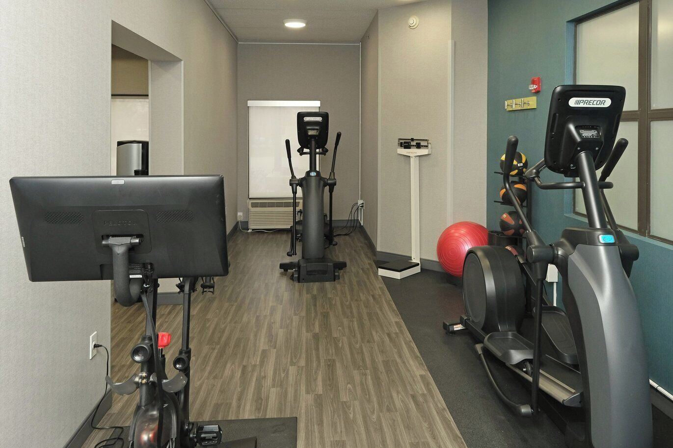 Een fitnessruimte met loopbanden, een elliptische trainer, een hometrainer en een rode fitnessbal.