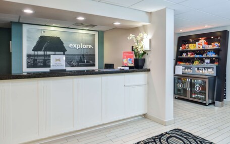 A reception area with a counter, a large window displaying a beach scene, and a vending machine with snacks.