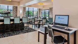 Una camera d'albergo con una scrivania, un computer e diverse sedie.