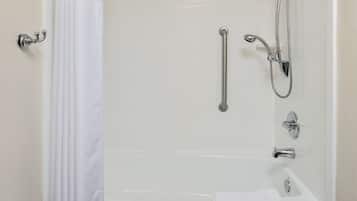 Eine weiße Badewanne mit Duschbrause, Haltegriff und Handtuch am Rand.