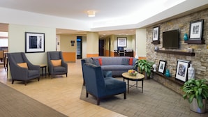 A lobby with seating, a TV, and framed pictures on the wall. - Hotel Carlisle (Carlisle)