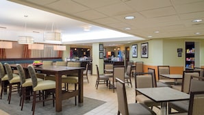 A restaurant with multiple dining tables and chairs, a counter with a menu, and a wall with framed pictures. - Hotel Carlisle (Carlisle)