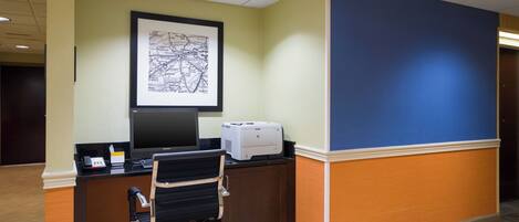 A reception desk with a computer, printer, and framed map on the wall.