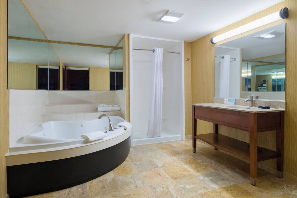 A modern bathroom with a freestanding bathtub, a walk-in shower, a vanity with a mirror, and a large mirror above the vanity.