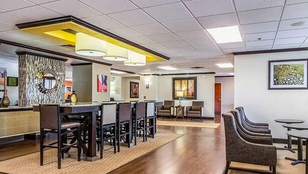 A hotel lobby with a reception desk, seating area, and a coffee station.