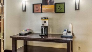 A reception area with a coffee machine, a framed poster, and wall-mounted lights.