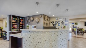 A reception area with a counter, a snack bar, and a wall decorated with framed certificates and artwork. - Best Western North Phoenix Hotel (Phoenix)