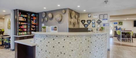 A reception area with a counter, a snack bar, and a wall decorated with framed certificates and artwork.