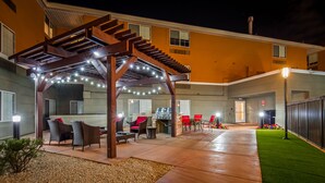 An outdoor patio area with a covered seating area, a barbecue grill, and a well-lit entrance. - Best Western North Phoenix Hotel (Phoenix)