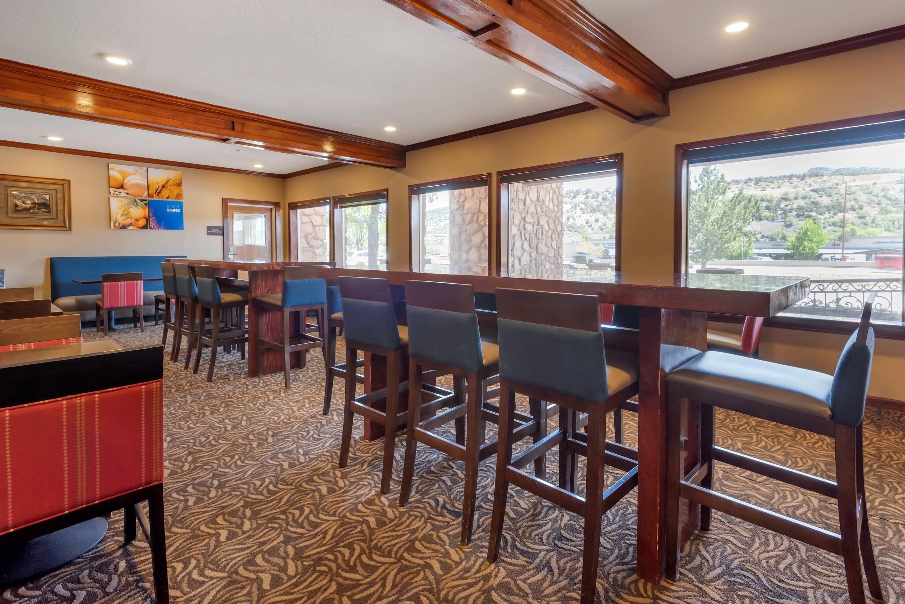 A restaurant with wooden bar stools and a patterned carpet.