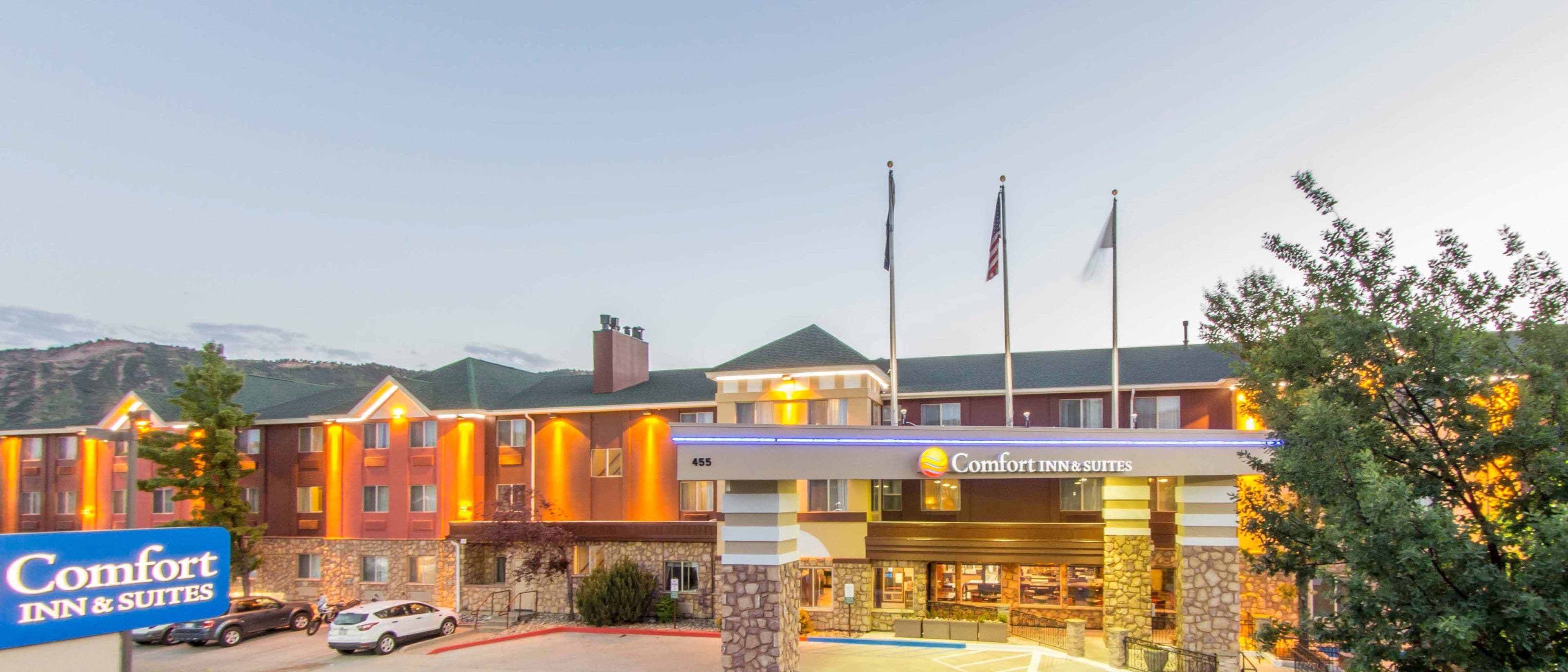 A Comfort Inn & Suites hotel with a stone facade, multiple flags, and a parking lot.