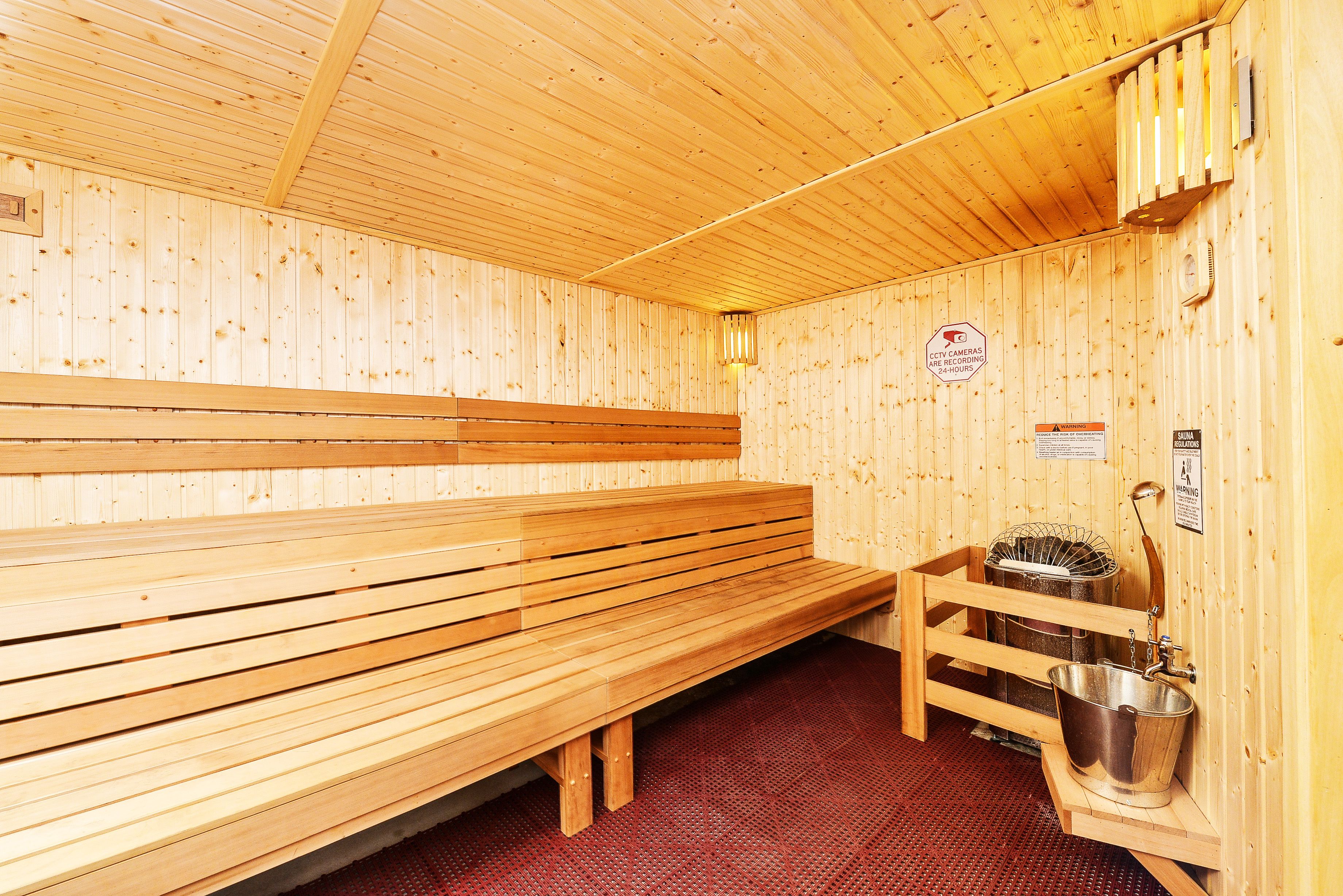 Ein Sauna-Raum mit Holzbänken und einem Metall-Eimer.