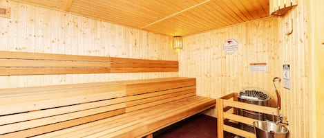 Ein Sauna-Raum mit Holzbänken und einem Metall-Eimer.