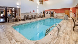 An indoor swimming pool with clear lane markings, a lifeguard chair, and a tiled floor.