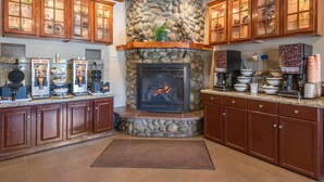 A kitchen with a stone fireplace, wooden cabinets, and coffee-making equipment.