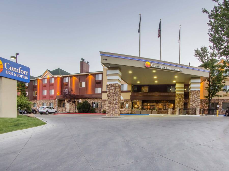 Un Comfort Inn & Suites amb façana de pedra, diverses banderes i una entrada ben il·luminada.