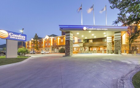 A Comfort Inn & Suites with a well-lit entrance, stone pillars, and flags.