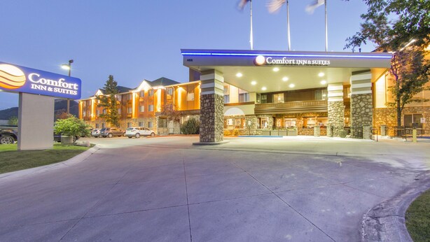 A Comfort Inn & Suites with a well-lit entrance, stone pillars, and flags.