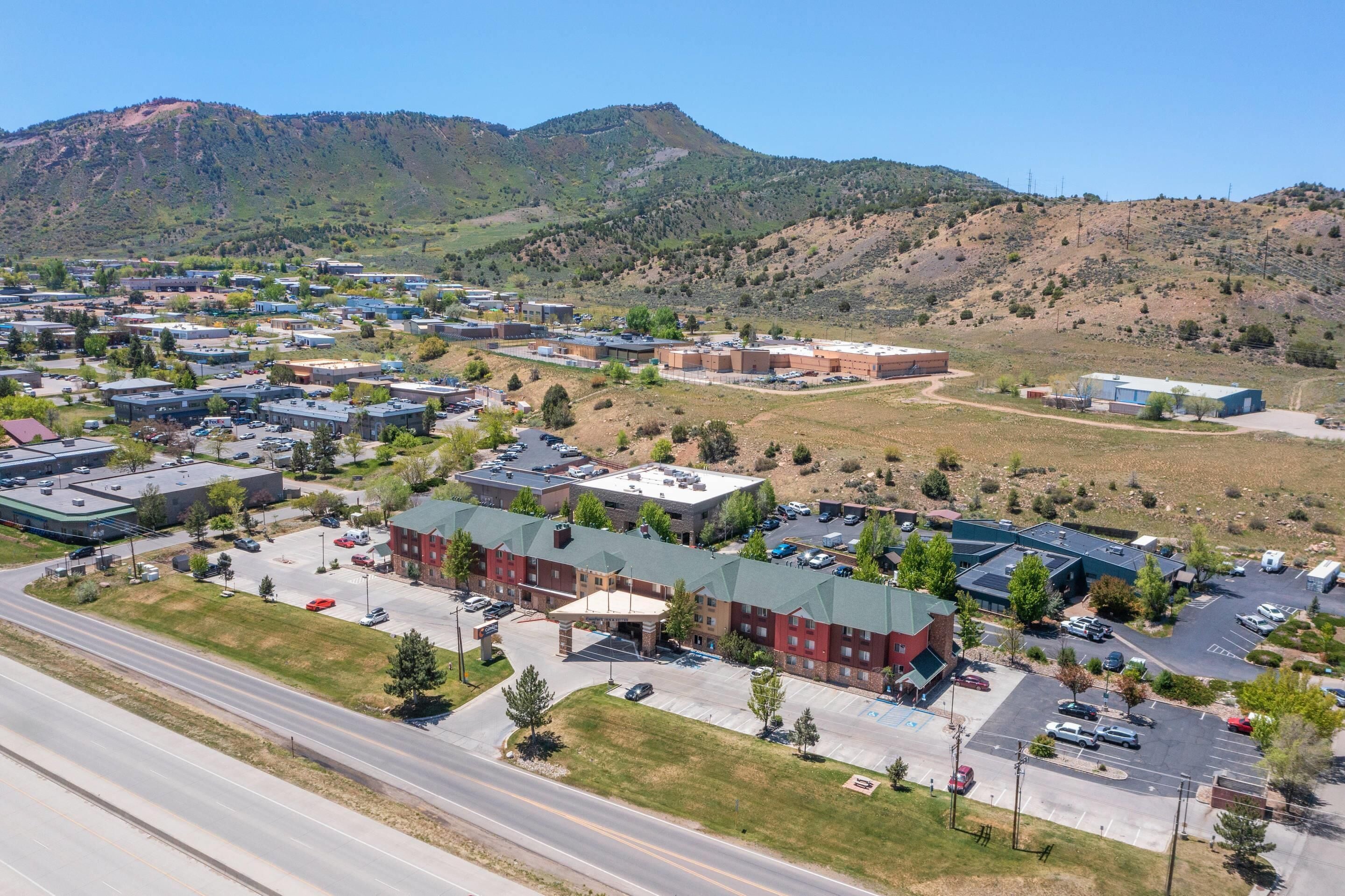 An aerial view of a commercial area with multiple buildings, parking lots, and a road.
