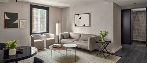A modern living room with a sofa, chairs, a coffee table, and artwork on the walls.