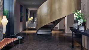 Un interno moderno con una scala a forma di arco, un muro in mattoni e un pannello illuminato di grandi dimensioni.