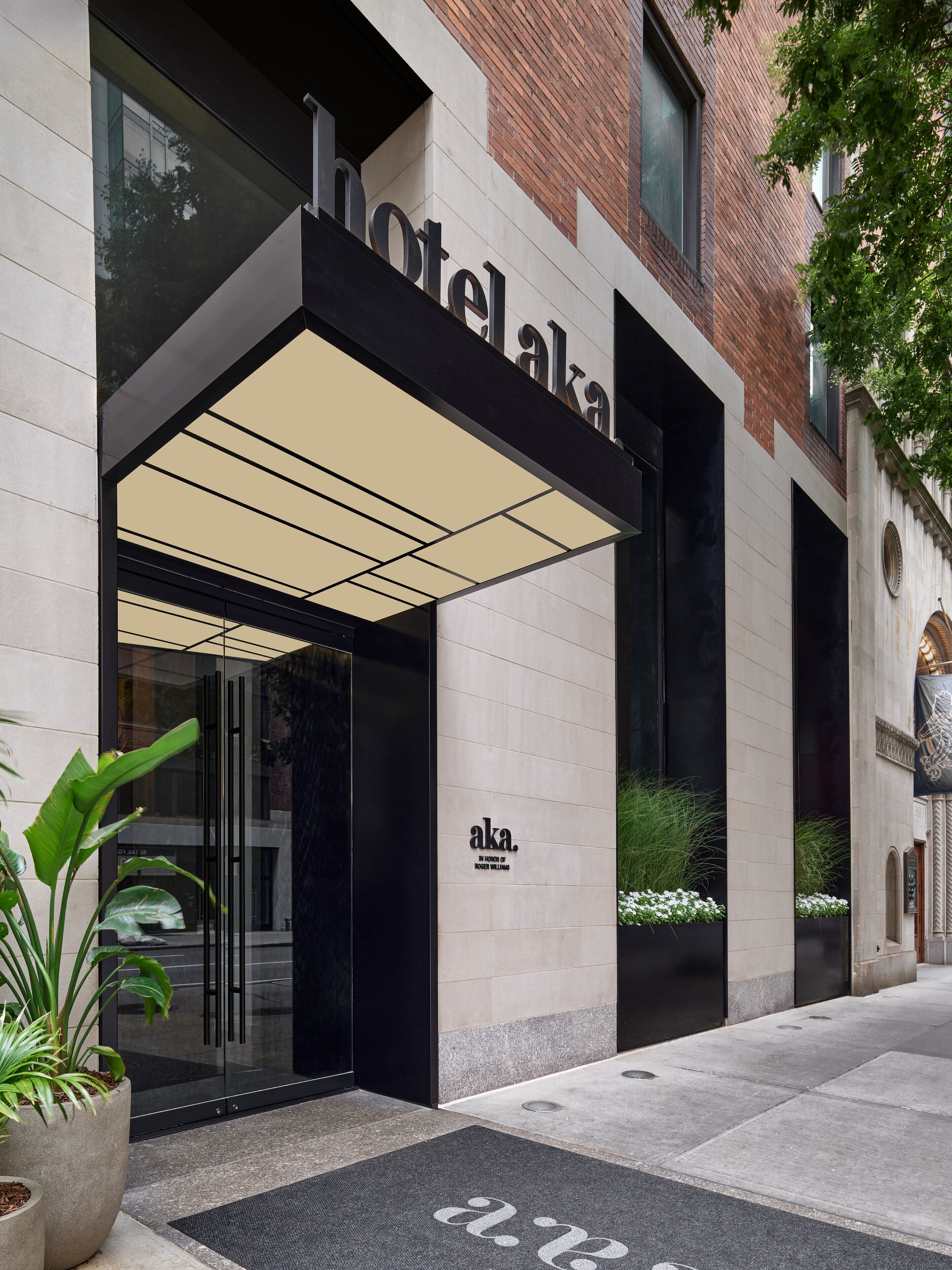 A hotel entrance with a modern design, featuring a glass facade and a prominent sign.