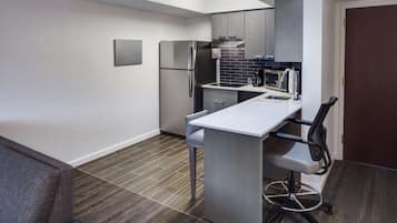 A compact kitchen with a built-in refrigerator, microwave, and sink.