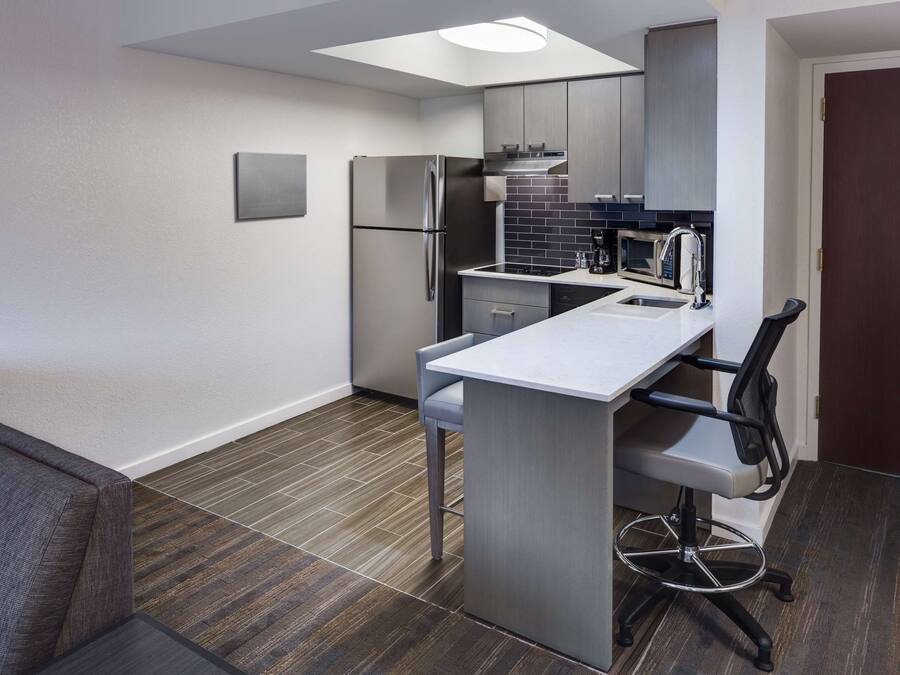 A compact kitchen with a built-in refrigerator, microwave, and sink.