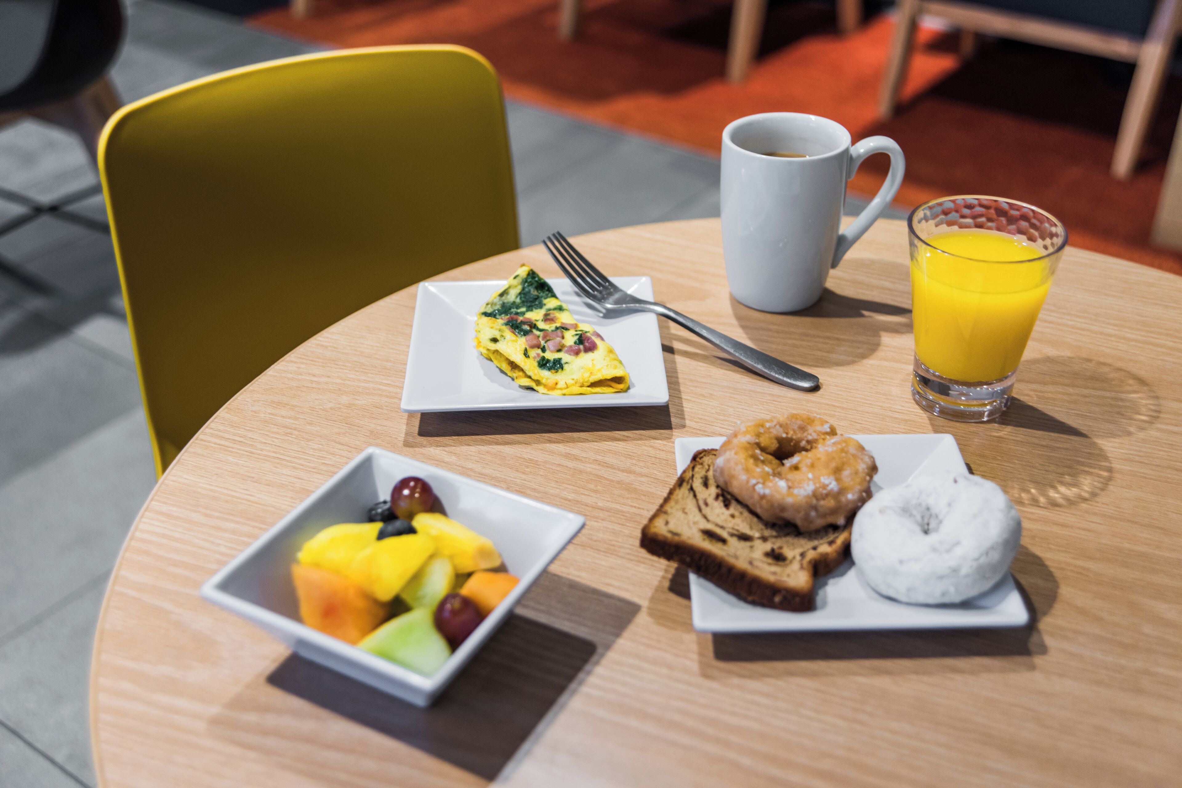 A breakfast setting with a plate of food, a glass of orange juice, and a cup of coffee on a wooden table.