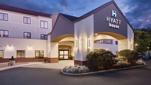 A modern hotel with a prominent 'Hyatt House' sign, featuring a symmetrical facade, large windows, and a landscaped entrance area. - HYATT house Boston/Waltham (Waltham)