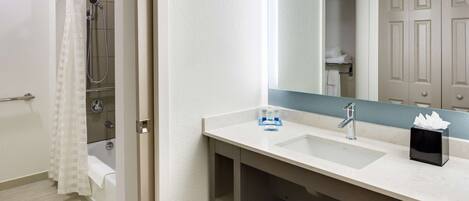 A modern bathroom with a shower, a sink, and a mirror.
