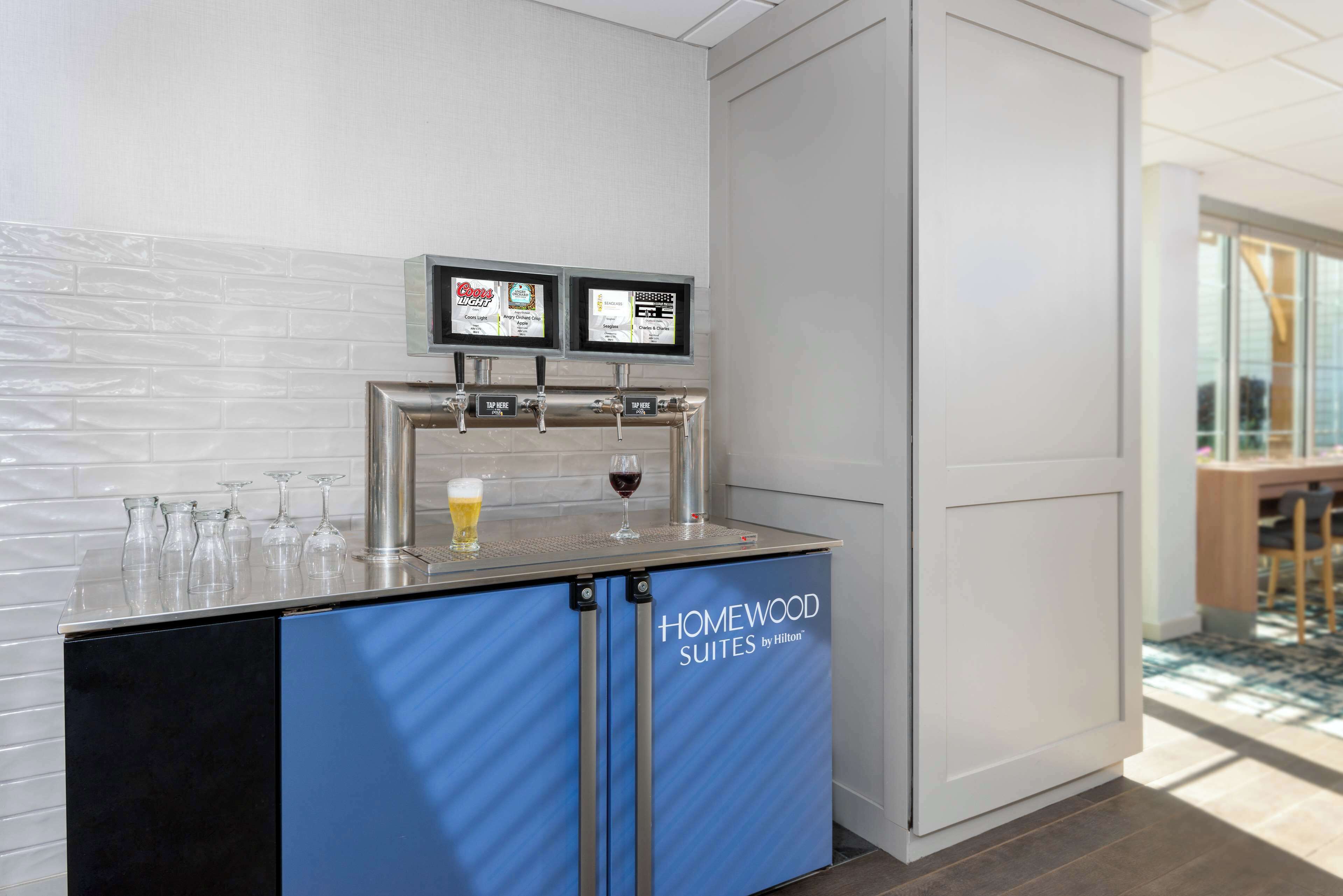A minibar with a wine dispenser and two screens displaying content.